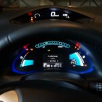 El tablero digital de un coche eléctrico encendido, mostrando indicadores azul brillante, el mensaje "To 100% Charge" y el velocímetro en cero tras recibir energía.